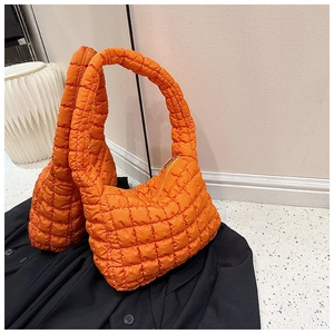 Detail of orange quilted puffer bag with square bubble texture and zipper closure