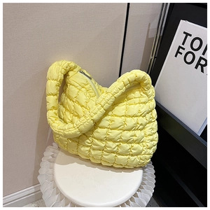 Detailed view of the quilted puff shoulder bag in pale yellow fabric with a zipper closure