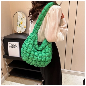 Detail of emerald green quilted puffer tote bag showing soft texture and wide shoulder strap