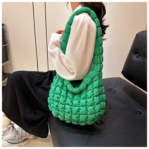 Detail of emerald green quilted tote bag with pleated cloud texture on model shoulder