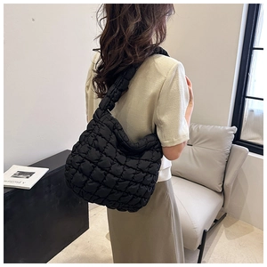 Rear view of a model wearing a large black quilted tote bag with pleated cloud design