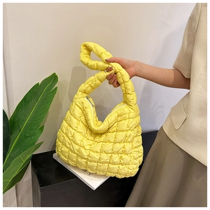 Detail of yellow quilted cloud tote bag with puffy texture and silver zipper handle