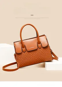 Close-up of caramel woven tote bag with smooth faux leather trim and metallic logo detail