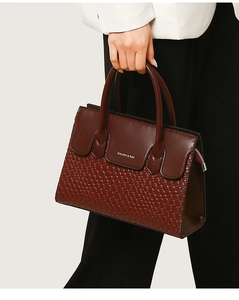 Detail of burgundy leather tote bag featuring woven scale texture and brand logo