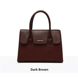 Detail of dark brown tote bag with crocodile pattern texture and hard round handles