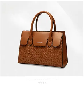 Detail of brown tote bag featuring textured faux crocodile skin and smooth leather finish