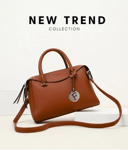 Détail de la texture cuir litchi marron et du pendentif en métal rond sur le sac