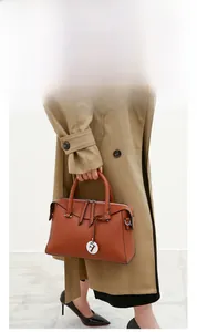 Détails d'un sac à main en cuir marron grainé avec ferrures argentées et pendentif