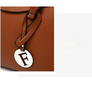 Gros plan d'un sac en cuir grainé marron avec un pendentif métallique en forme de F