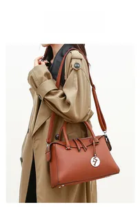 Détail du sac à main en cuir marron caramel avec pendentif lettre F et bandoulière