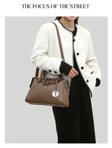 Détail d'un sac à main en cuir marron foncé avec deux poignées et charm lettre F