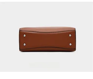 Détail du fond d'un sac en cuir marron grainé avec des clous de protection en argent