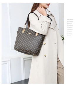 Détail du sac cabas marron imprimé avec plaque dorée porté par un mannequin élégant