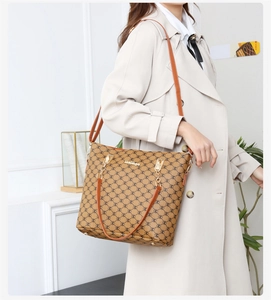 Grand sac cabas marron à motif monogramme et détails dorés porté par un mannequin