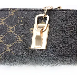 Détail des poignées renforcées et boucle dorée sur sac à main marron foncé avec motif M