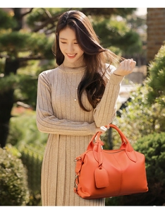 Borsa a mano arancione vivace in pelle indossata da modella in abito, stile urbano