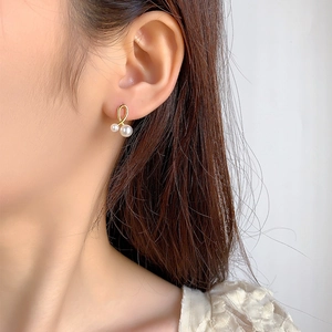 Elegant gold twisted pearl drop earrings featuring large and small pearls on model