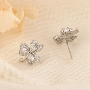 Close-up of silver clover earrings with cubic zirconia inlay and heart-shaped petals