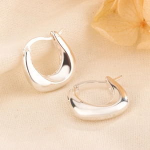 Polished silver U-shaped chunky hoop earrings with S925 hallmark on beige fabric