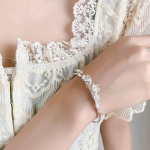 Detailed view of plum blossom branch open bangle with white flowers on wrist