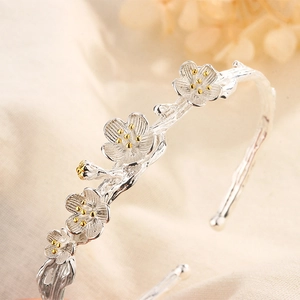 Macro view of plum blossom bangle with silver petals and gold stamen details