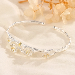 Macro detail of plum blossom silver cuff bracelet featuring 3D branch texture and gold stamens