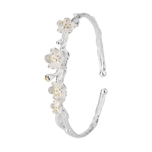 Macro shot of silver plum blossom branch bracelet with textured relief and gold pistils