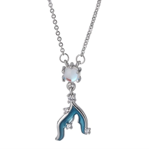 Macro shot of silver fishtail pendant with moonstone, blue enamel, and sparkling zircons