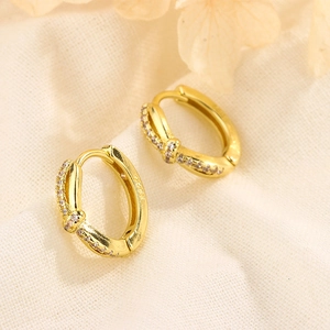 Close-up of S925 sterling silver stamp on golden knotted hoop earrings with crystals
