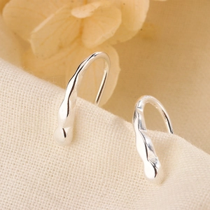 Close-up of silver geometric ear hooks with textured liquid metal surface on linen