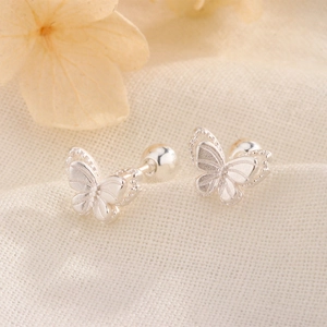 Detail of butterfly screw-back earrings with matte silver texture on white fabric