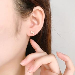 Détail de boucles d'oreilles papillon avec monture dorée et pierres d'opale irisées