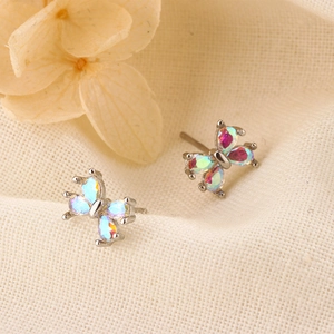 Vue macro de boucles d'oreilles papillon rose avec ailes irisées et finition argentée