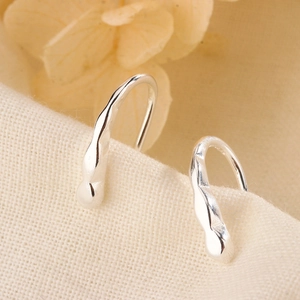 Minimalist silver irregular fluid teardrop earrings on textured fabric background