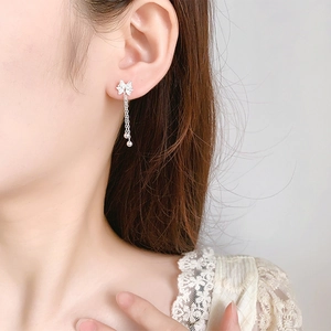 Detail of silver bow tassel earrings on model showing elegant drape and filigree