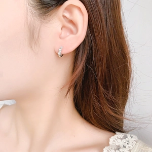 Close-up of a silver floral earring with cubic zirconia on a model's ear