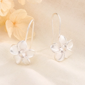 Detail of silver floral earrings with matte brushed finish and sparkling center zircon