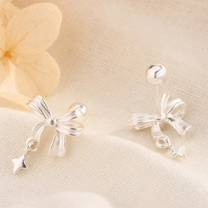 Macro detail of silver bow earrings with star pendants and secure screw ball backs
