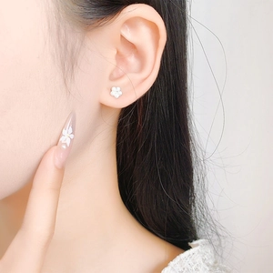 Close-up of elegant small white flower stud earrings worn on model for casual style