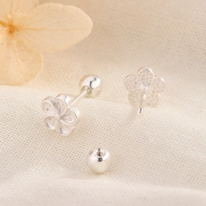 Close-up of minimalist silver flower stud earrings with secure screw-back design