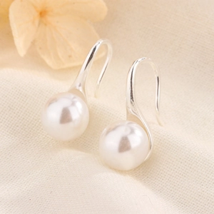 Gros plan d'élégantes boucles d'oreilles en perles d'eau douce sur tissu beige
