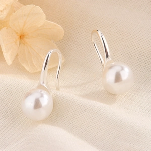 Vue détaillée d'élégantes perles d'eau douce blanches sur crochets en argent sur lin