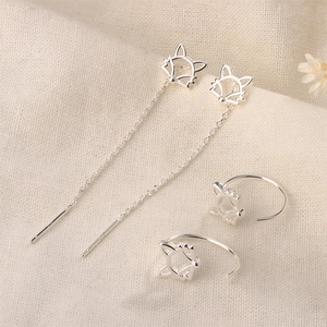 Detailed view of silver fox hollow tassel earrings and C-shaped studs on beige linen texture