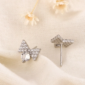 Macro detail of silver bow earrings featuring shimmering pavé set white cubic zirconia