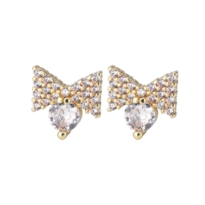 Close-up of golden bow stud earrings with intricate cubic zirconia stone inlay