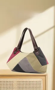 Detail view of large canvas tote bag with multi-color geometric patchwork and leather handles