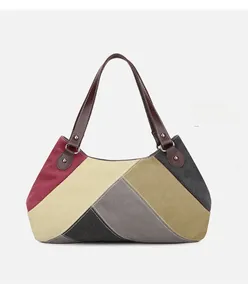 Detail of color-block canvas tote bag showing geometric patterns and metal rivets