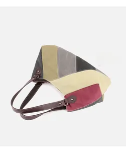Detail of color-block canvas tote bag with brown leather straps and rivet accents