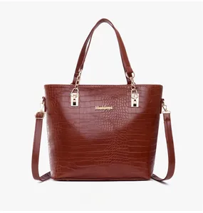 Détails d'un sac à main marron effet crocodile avec logo doré et accessoires