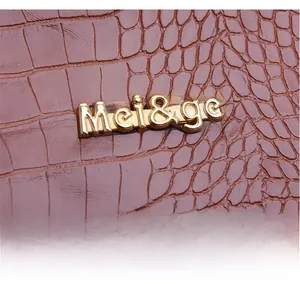 Gros plan sur la texture crocodile marron et le logo doré de ce sac à main chic